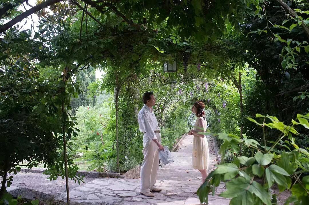 魔力月光-男女主角在绿意盎然的花园小径上交谈