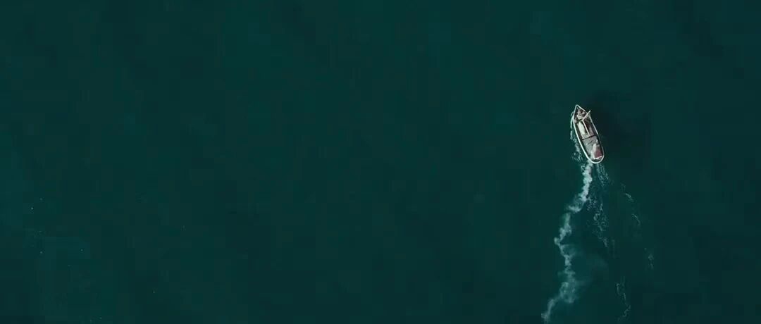 大洋之间的灯光-一艘小船在广阔的海面上航行，留下一道白色的尾迹