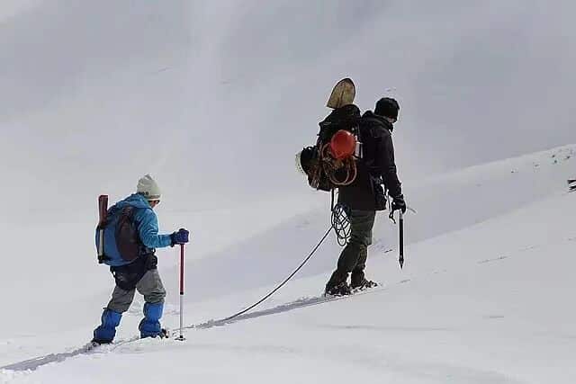 背负春天-登山者在雪地中艰难攀登，背负着沉重的装备