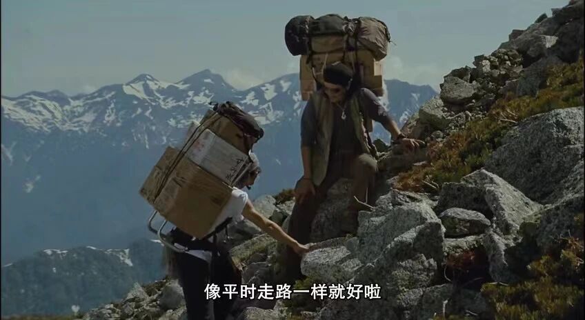 背负春天-两位登山者在崎岖的山路上艰难攀登，背着沉重的物资