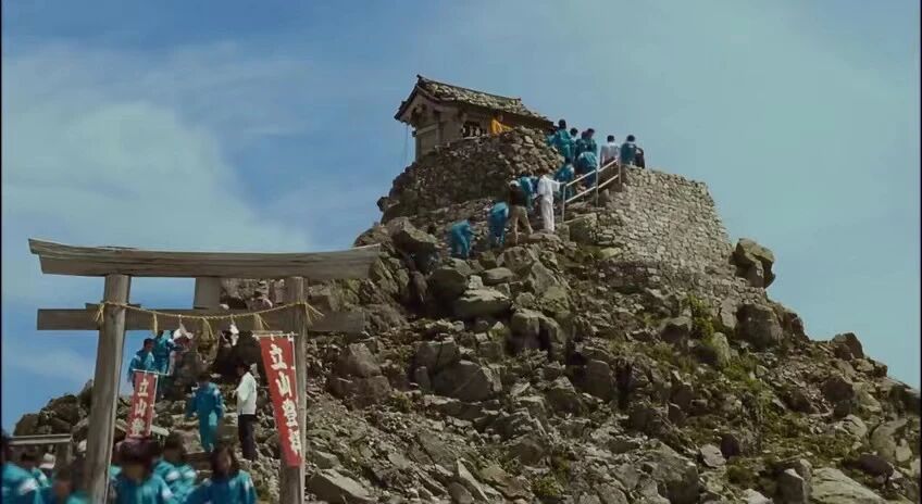 背负春天-登山者们聚集在山顶的神社前，庆祝登顶成功