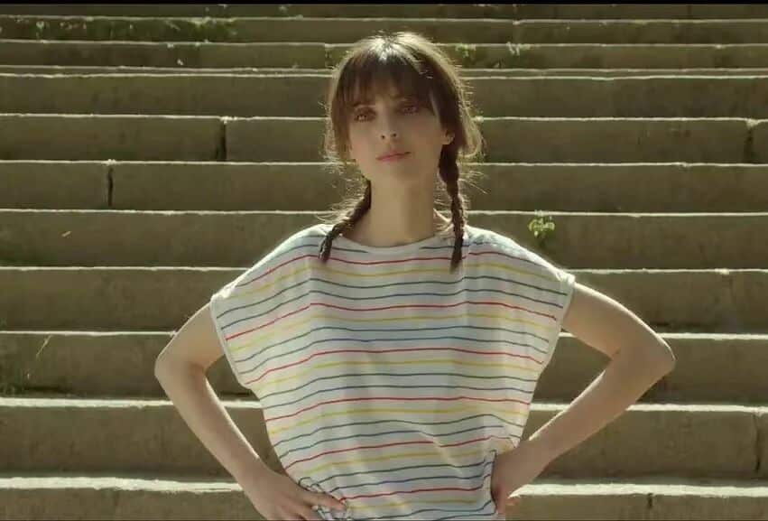 普通人行为指南女主角站在户外的台阶前，双手叉腰，穿着彩色条纹T恤