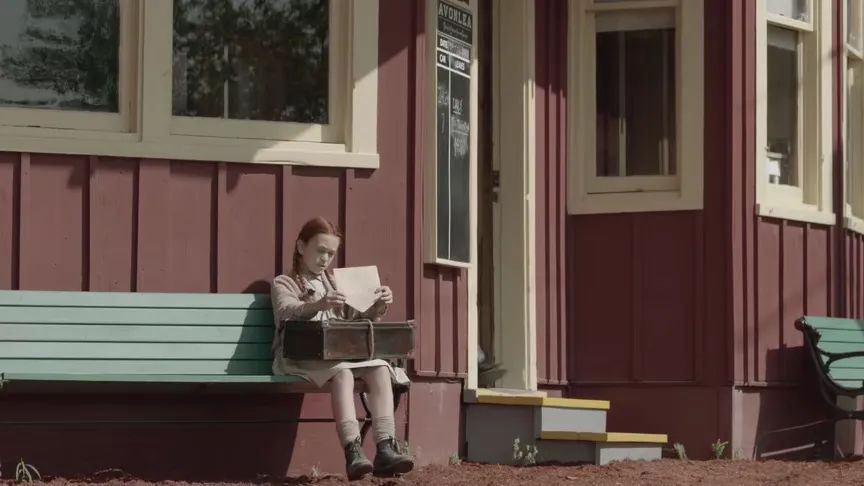 清秀佳人女主角坐在火车站外的长椅上阅读信件